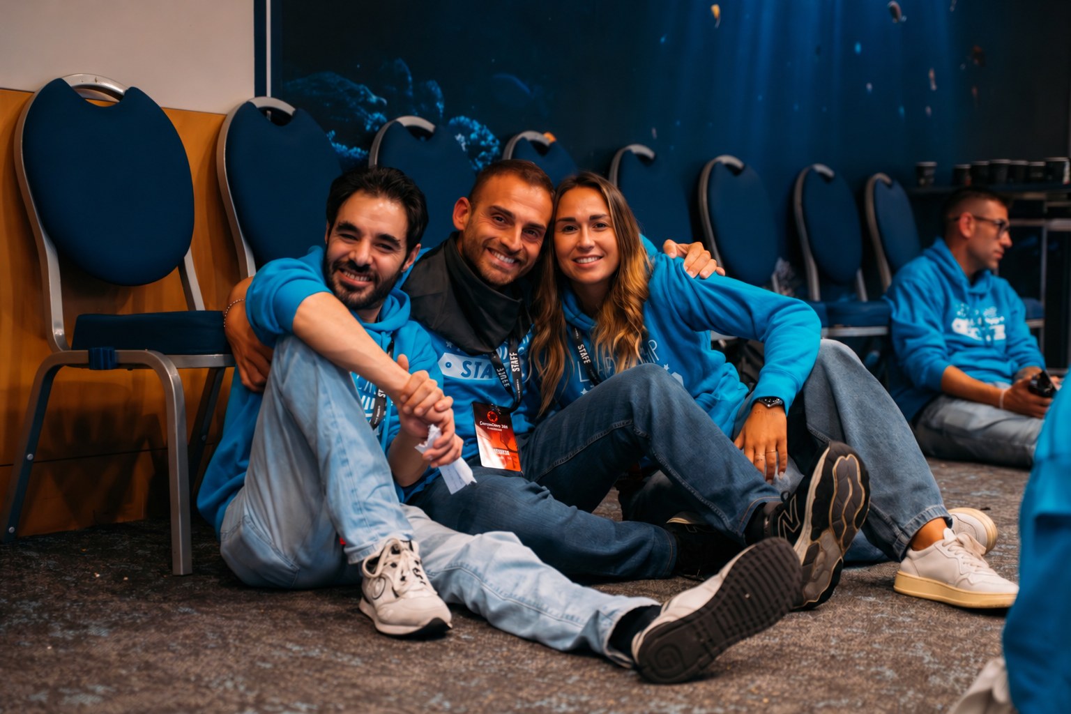 Tre membri dello staff seduti tra le file della sala